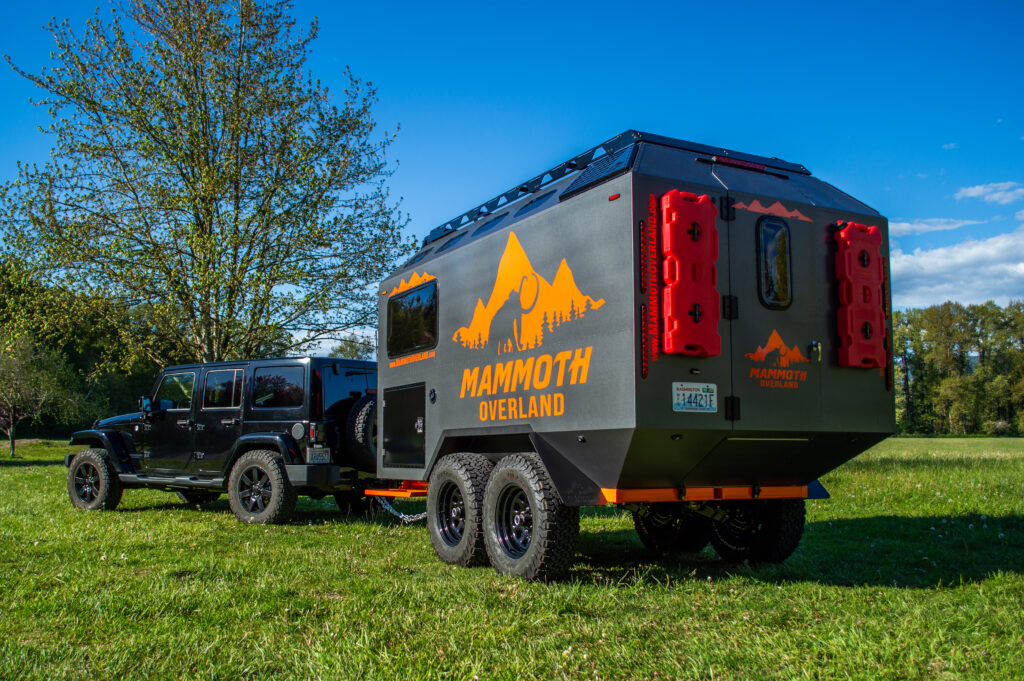 Mammoth Overland TL off-road trailer towed by a Jeep Wrangler in a grass field